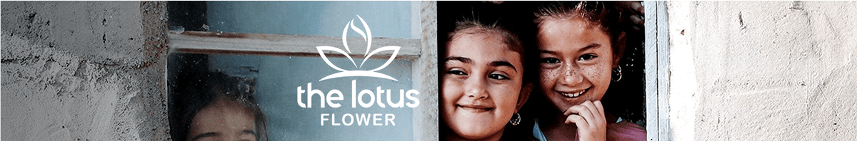 Three smiling girls peek out from behind a white wall and window. The logo and text the lotus flower with a lotus graphic are displayed on the window pane. The scene appears bright and friendly.