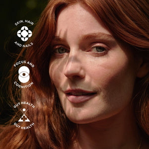 A woman with long red hair stands in sunlight with leaf shadows on her face. Three icons and text on the left read: Skin, Hair and Nails, Focus and Cognition, and Gut Health.