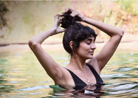 Young lady standing in a lake tying her hair