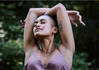 Women with shaved head and nose ring standing outside taking a deep breath