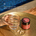A hand holds a glass of water beside an Ancient + Brave True Ashwagandha jar and three capsules on a gold tray. Text above provides dosage instructions and recommends pairing with Triple Magnesium+ to help restore balance.