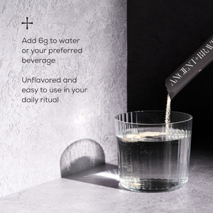 Glass being filled with a liquid from a True Creatine sachet on a neutral background.