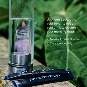 A glass bottle with a crystal sits on greens next to two Ancient + Brave True Collagen Sachets, which feature hydrolyzed bovine collagen for whole body health. The neutral-tasting powder mixes easily into any drink.
