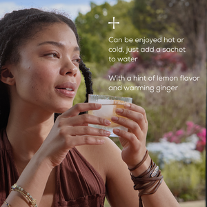 A woman sits outdoors holding a light drink. Text reads: Enjoy Ancient + Brave True Nightcap Sachets hot or cold—just add to water. With targeted nutrients, lemon flavor, and warming ginger. Flowers and greenery appear in the background.