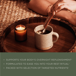 A person stirs a mug of Daily Wellness Ritual by Ancient + Brave on a wooden tray beside a lit candle. Text below highlights benefits: supports daily nourishment, enhances your wellness ritual, and is rich in targeted nutrients.