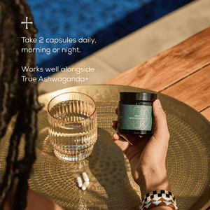 A person holds a jar labeled True Magnesium+ next to a glass of water and two white capsules on a golden tray by a pool. Text reads: Take 2 capsules daily, morning or night. Works well alongside True Ashwaganda+.