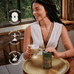 A smiling woman sits at a table with a golden tray, holding a green drink and a green container. Text beside her reads: Matcha + Collagen by Ancient + Brave — supports focus, cognition, mobility, recovery, energy, and performance.