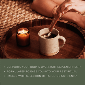 A hand stirs a mug of hot beverage with a wooden spoon next to a lit candle on a woven surface. Text highlights the drinks benefits for overnight replenishment, rest, and nutrients.